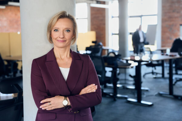 na zdjęciu kobieta oparta o filar, w tle biuro