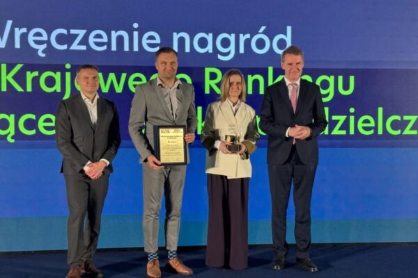 na zdjęciu trzech mężczyzn i kobieta w środku, w tle napis wręczenie nagród Krajowego rankingu wyróżniające się banki spółdzielcze